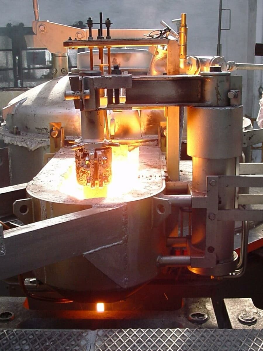 Close-up of the sealed CAP furnace body and its stopper-rod mechanism, glowing metal at the heated discharge siphon
