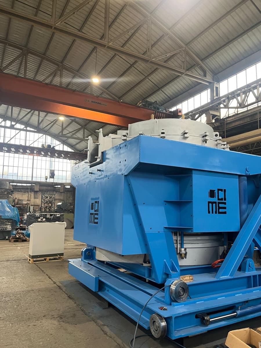 The body of a CIME coreless induction furnace in the workshop, coil and refractory crucible enclosed inside the blue steel shell on its tilting frame