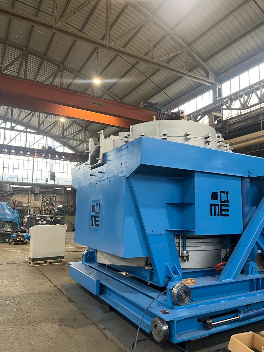 A blue CIME-branded CAP press-pouring furnace assembly mounted on its carriage inside a daylit foundry workshop